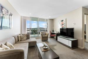 uma sala de estar com um sofá e uma televisão de ecrã plano em CBD 2BR Apartment at 96 North Tce - Free Parking em Adelaide