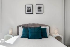 a bedroom with a white bed with blue pillows at The amazing 1BR CBD Apt Premium Location in Adelaide