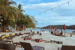 a beach with chairs and people on the sand at Pak Nam Resort in Satun