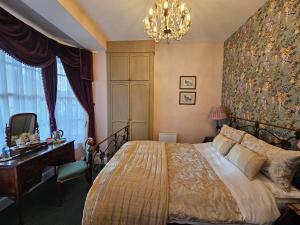 a bedroom with a bed and a desk and a chandelier at Mostyn House in Llandudno