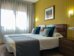 ein Hotelzimmer mit 2 Betten und einem Fenster in der Unterkunft Hotel Arcos Catedral in Ciudad-Rodrigo