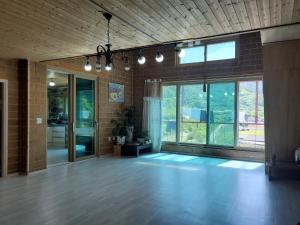 an empty room with a large window and a room with wooden floors at Danyang Wepoongdangdang Pension in Danyang
