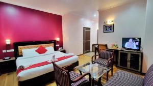 a hotel room with a bed and a flat screen tv at Hotel Marc Mall Road Shimla - Family Friendly & Parking - A Four Star Luxury Hotel Mountain View in Shimla
