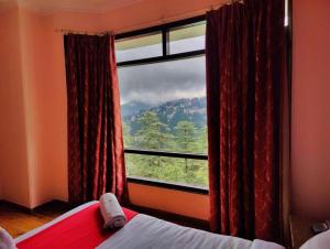 a bedroom with a window with a view of a mountain at Hotel Marc Mall Road Shimla - Family Friendly & Parking - A Four Star Luxury Hotel Mountain View in Shimla