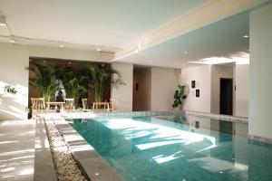 a large swimming pool with blue water in a building at The Rise Suites Hotel, Chiang Mai - SHA Extra Plus in Chiang Mai