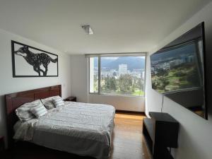 ein Schlafzimmer mit einem Bett und einem großen Fenster in der Unterkunft Five Stars Suites - Park - Quito in Quito