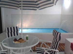 une table et deux chaises avec une table et un parasol dans l'établissement Departamento en playa Chocaya. Disfruta del mar, la piscina y la tranquilidad., à Asia