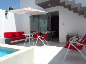 une terrasse avec une table, des chaises et un parasol dans l'établissement Departamento en playa Chocaya. Disfruta del mar, la piscina y la tranquilidad., à Asia