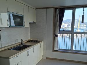 a kitchen with a sink and a window with a view at Yeosu Rex Haesoo Resort in Yeosu