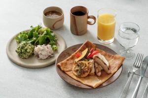 uma mesa com dois pratos de comida e um copo de sumo de laranja em KIRO Hiroshima by THE SHARE HOTELS em Hiroshima