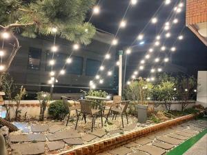 a patio with a table and chairs and lights at Yeosu Sonamu Pension in Yeosu