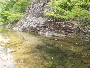 a river next to a rocky cliff with trees at Sangjoo munjangdae healing house in Sangju