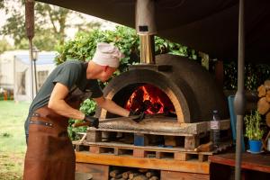Een man in een schort die een bakstenen oven bouwt. bij Trekkershut Plus voor 5 personen incl keuken in Zwiggelte