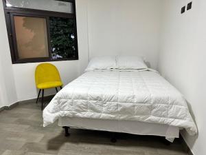 um quarto com uma cama e uma cadeira amarela em Hotel Terravolcan em La Tenería