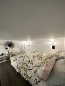 a bedroom with a large bed with a white wall at NEW! Sea Joley Tiny Home in Nelly Bay