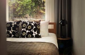 a bed with black and white pillows and a window at Ilo Pension in Seogwipo +10 photos