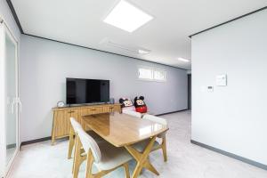 a dining room with a table and a flat screen tv at Gapyeong Meegasheel Family Pension in Gapyeong