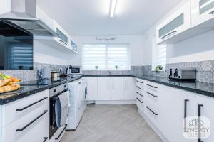 uma cozinha com armários brancos e bancadas pretas em Sapphire House, Manchester - by Synergy Estates em Manchester
