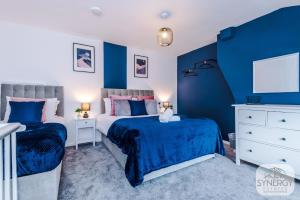 Duas camas num quarto com paredes azuis em Sapphire House, Manchester - by Synergy Estates em Manchester