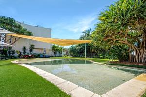 a swimming pool with a wooden shade in a yard at Absolute Beachfront Penthouse - Ramada Marcoola in Marcoola
