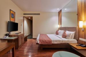 a hotel room with a bed and a flat screen tv at Hotel Studio Estique in Pune