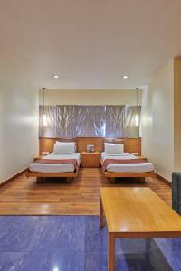 two beds in a room with wooden floors at Hotel Studio Estique in Pune