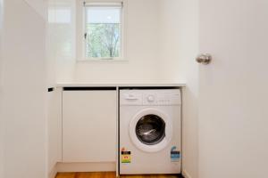 een wasmachine in een witte kamer met een raam bij Peaceful Home in the Prime Greenlane in Auckland