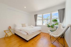 een witte slaapkamer met een bed en een stoel bij Peaceful Home in the Prime Greenlane in Auckland