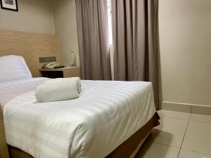 Living At DSulaiman Hotel في كوالالمبور: غرفة نوم بسرير ابيض مع هاتف