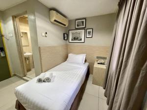 Living At DSulaiman Hotel في كوالالمبور: غرفة صغيرة عليها سرير وفوط