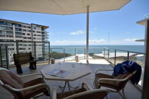 balcón con mesa, sillas y vistas al océano en Redvue Holiday Apartments, en Redcliffe