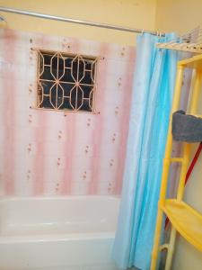a bathroom with a window and a shower curtain at Boothe's Palace in Oracabessa