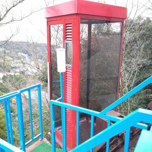 Czerwona budka telefoniczna siedząca na szczycie wzgórza w obiekcie ゴンドラヴィラ イン熱海 w mieście Atami