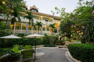 une terrasse avec des chaises et un parasol en face d'un bâtiment dans l'établissement At Pingnakorn Riverside, à Chiang Mai