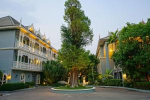 a large building with a tree in front of it at At Pingnakorn Riverside in Chiang Mai