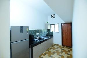 a kitchen with a white refrigerator and a black counter top at Lourels Stay in Udupi