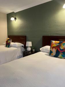 - une chambre avec 2 lits et un mur vert dans l'établissement Inari Hostal, à Guatemala