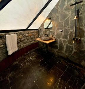a stone bathroom with a sink and a mirror at Orange Loft, Glamp Park Murree in Murree