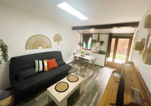 ein Wohnzimmer mit einem schwarzen Sofa und einem Tisch in der Unterkunft Au pied des Remparts 10 rue Saint jean in Villefranche-de-Conflent