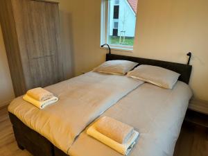 1 cama grande con 2 toallas encima en Modern holiday home in Scherpenisse with infrared sauna, en Scherpenisse