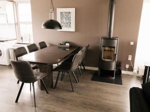 ein Esszimmer mit einem Tisch, Stühlen und einem Kamin in der Unterkunft Holiday home Satijnduiker in Makkum
