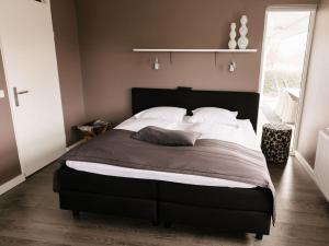 a bedroom with a large bed with white pillows at Holiday home Satijnduiker in Makkum