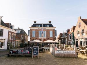 eine Stadtstraße mit einem Gebäude, Tischen und Sonnenschirmen in der Unterkunft Holiday home Satijnduiker in Makkum