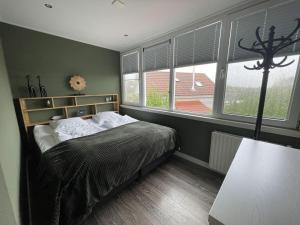 um quarto com uma cama num quarto com janelas em Holiday apartment Rietzanger for 10 peop em Makkum