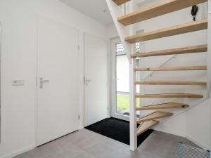 Una escalera en una habitación blanca con ventana en Beautiful holiday home with lots of space in a holiday park near Alkmaar, en Hensbroek