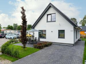 a white house with a patio in a parking lot at Beautiful holiday home with lots of space in a holiday park near Alkmaar in Hensbroek