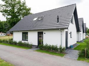 een wit huis met een zwart dak op een straat bij Beautiful holiday home with lots of space in a holiday park near Alkmaar in Hensbroek