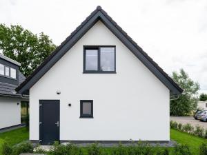een wit huis met zwarte ramen en een zwarte deur bij Beautiful holiday home with lots of space in a holiday park near Alkmaar in Hensbroek