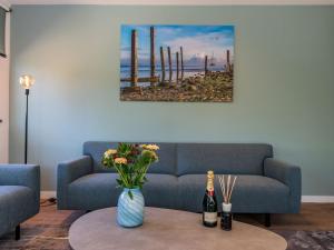 een woonkamer met een bank en een tafel met bloemen bij Beautiful luxurious villa situated in Den Burg in Den Burg