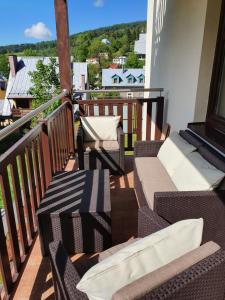 a balcony with wicker chairs and a view at Apartamenty City Center Cicha 8 in Krynica Zdrój